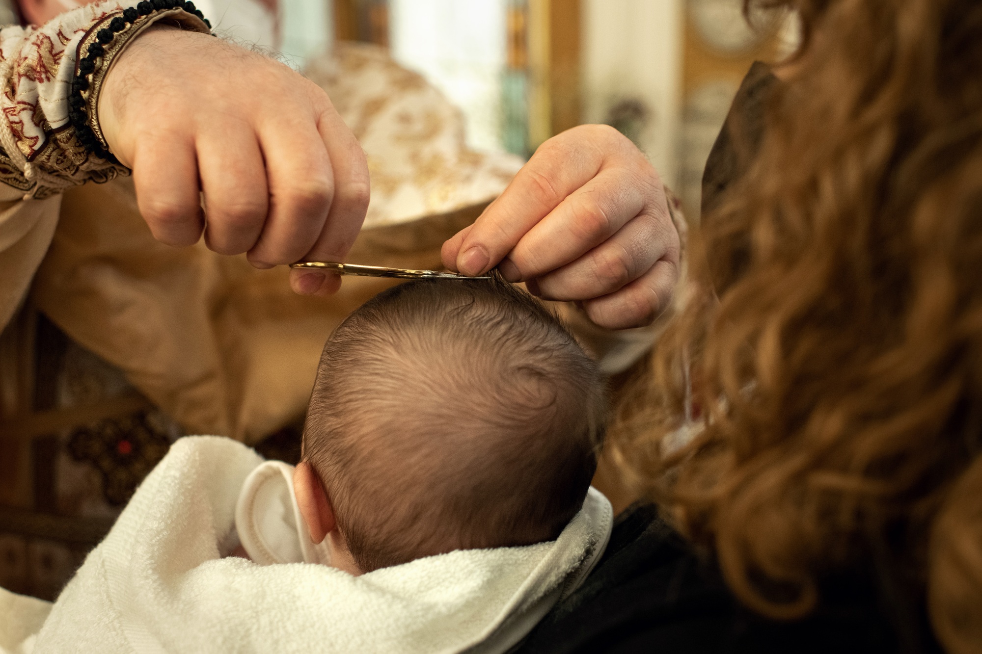 Godmother holds the baby the priest conducts a ceremony hair cut